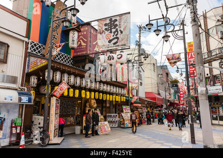 Osaka, Shinsekai, famosa area del centro cittadino, foreground, noodle bar con molti chochin, lanterne di carta e Billiken statua nella principale strada dello shopping. Ore diurne. Foto Stock