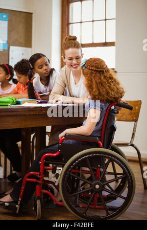 Docente aiutare una pupilla di disabili Foto Stock