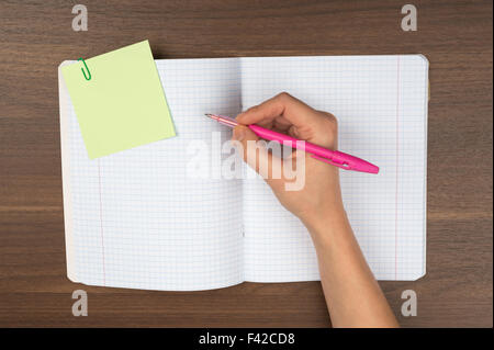 Womans mano che scrive sul tavolo Foto Stock