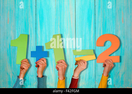 Le mani con la semplice equazione matematica contro blu parete in legno Foto Stock