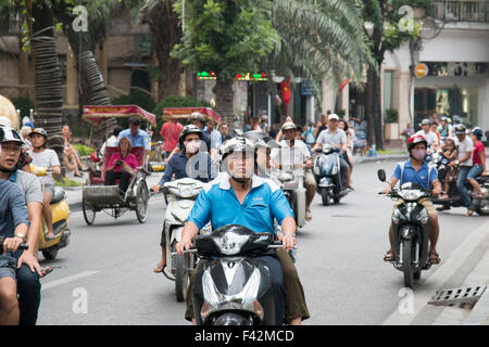 Il vietnamita su scooter passato di equitazione Lago Hoan Kiem ad Hanoi, capitale del Vietnam. Il cyclo piloti con i turisti a cavallo,Vietnam Foto Stock