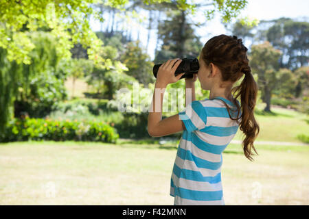 Carino bambina guardando attraverso il binocolo Foto Stock