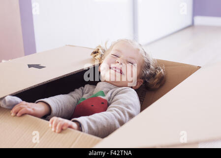Bambina giocando in una scatola di cartone, ritratto Foto Stock