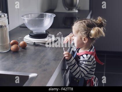 Little Girl holding frusta in cucina Foto Stock