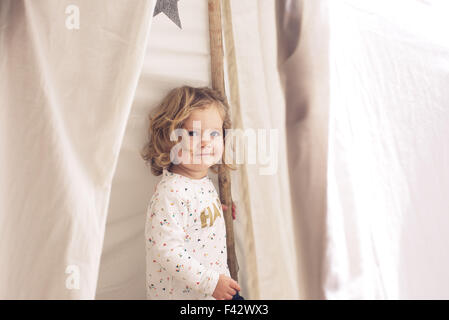 Piccola ragazza sorridente in tenda, ritratto Foto Stock