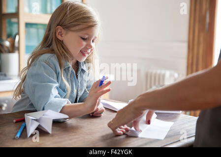 Bambina di imparare a fare aeroplano di carta Foto Stock