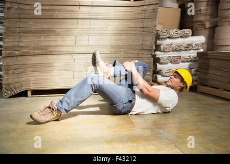 Lavoratore sdraiato sul pavimento in magazzino Foto Stock