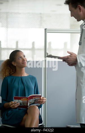 Donna che parla con il medico in sala d'attesa Foto Stock