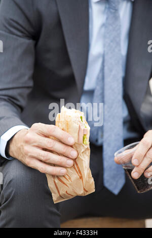 Imprenditore azienda sandwich, ritagliato Foto Stock