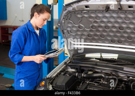 Mechanic utilizzando tablet per fissare l'auto Foto Stock