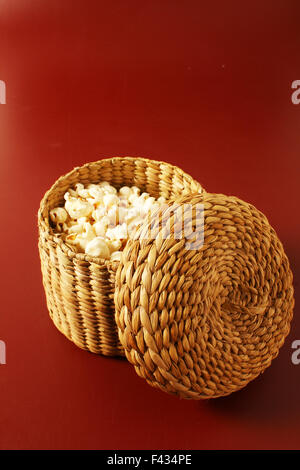 Il popcorn su sfondo rosso con cestello Foto Stock