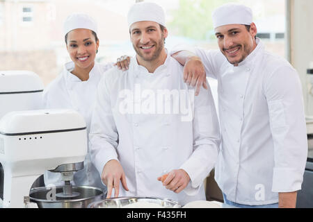 Team di fornai sorridente in telecamera Foto Stock