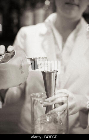Una donna di miscelare un cocktail, un mixologist al lavoro. Foto Stock