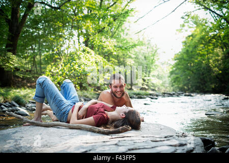 Un giovane uomo e donna sdraiata sulla roccia su una riva di un fiume. Foto Stock