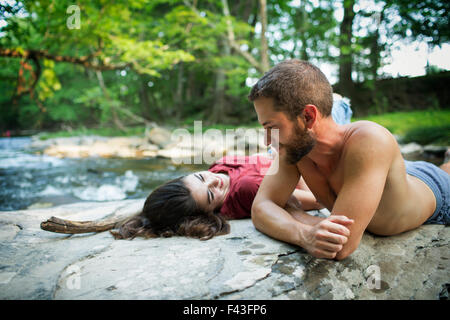 Un giovane uomo e donna sdraiata sulla roccia su una riva di un fiume. Foto Stock