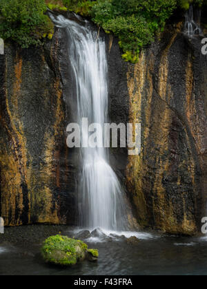 Cascate Hraunfossar, una cascata di acqua su una scogliera a strapiombo in una piscina. Foto Stock