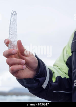 Una guida di trattenimento di un nucleo di ghiaccio campione dalla laguna glaciale nella sua mano. Foto Stock
