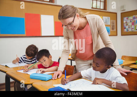 Piuttosto insegnante aiutando la pupilla in aula Foto Stock