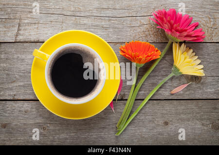 Tazza di caffè e gerbera fiori sul tavolo di legno Foto Stock