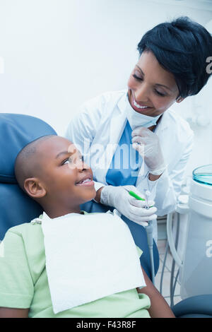 Donna sorridente dentista esaminando boys denti Foto Stock
