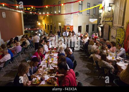 Lisbona, Portogallo - 23 ottobre 2014: persone aventi la cena all'aperto in calcada do Duque a Lisbona, con il castello Sao Jorge in bac Foto Stock