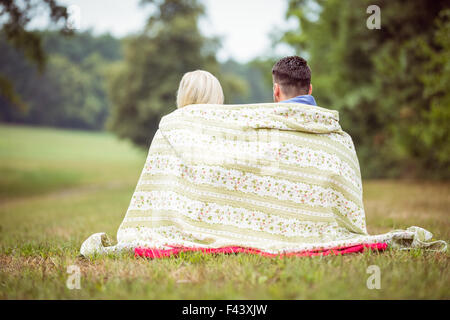 Coppia felice seduto sotto una coperta Foto Stock