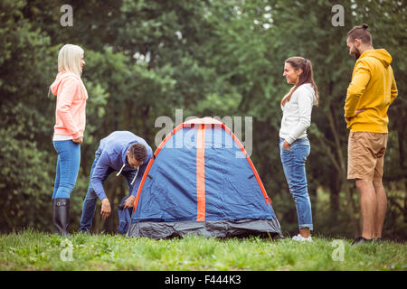 Happy amici impostazione della loro tenda Foto Stock