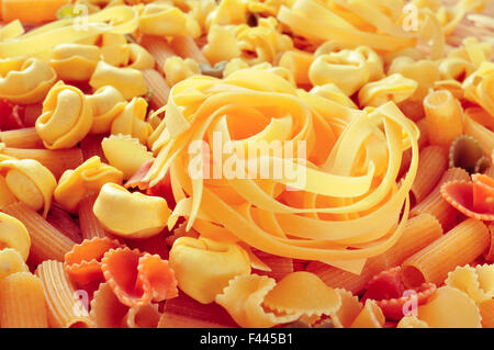 Primo piano di una pila di diverse paste alimentari non cotte come tortellini, tagliatelle o penne rigate Foto Stock