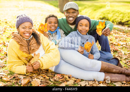 Giovane famiglia sorridente seduto in foglie Foto Stock