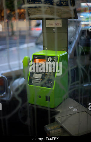 Pubblico a Pagamento di cabine telefoniche con telefono verde dietro il vetro di vandalismo Foto Stock