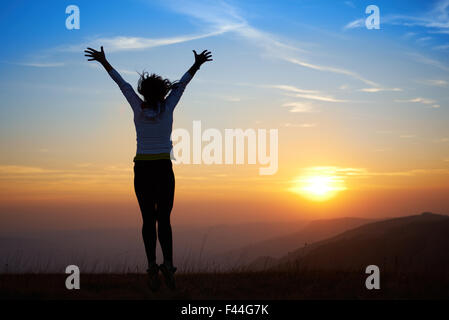 Silhouette di saltare la giovane donna Foto Stock