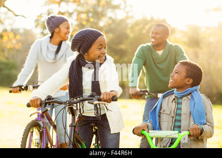 Giovane famiglia sorridente facendo un giro in bici Foto Stock