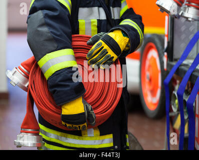 Vigile del Fuoco in azione con tubo flessibile per acqua Foto Stock