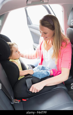 Madre che fissano il suo bambino nel seggiolino per auto Foto Stock