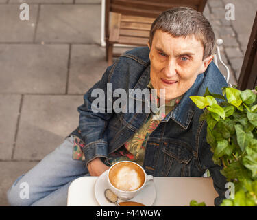 Disabilitato l'uomo con paralisi cerebrale seduto un cafe' all'aperto. Foto Stock