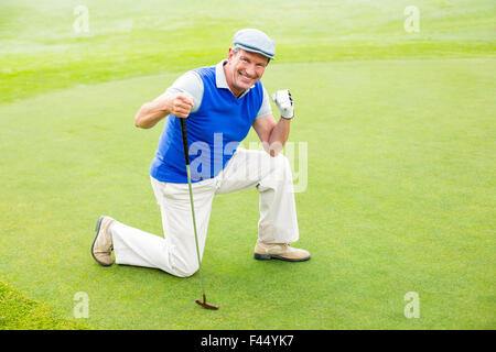 Sorridente golfista inginocchiato sul putting green Foto Stock