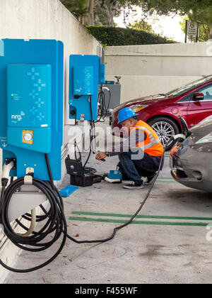 Tecnico di riparazione mantiene un auto elettrica stazione di ricarica a un Irvine, CA, ospedale parcheggio. Nota auto elettrica essendo caricato a destra. Foto Stock