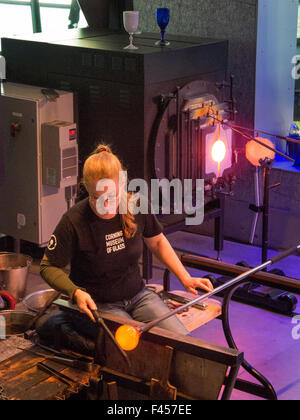 Utilizzando un attrezzo isolato, un glassblower o forme adesivo telato vetro fuso su un tubo prima della formatura in un oggetto presso il Museo del Vetro di Corning, NY. Nota forno ad alta temperatura. Foto Stock