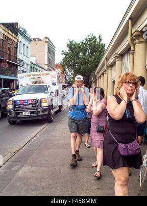 Pedoni fuori il famoso Mercato francese a New Orleans, LA, coprire i loro orecchi come ambulanza con una forte sirena li passa sulla strada. Foto Stock