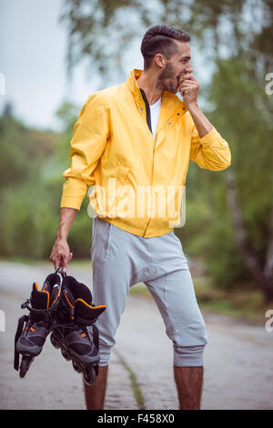 Uomo bello holding pattini inline Foto Stock