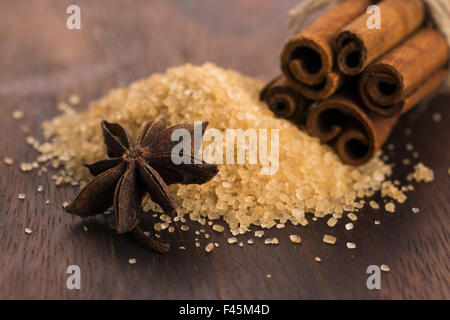 Bastoncini di cannella con puro di canna da zucchero marrone su uno sfondo di legno Foto Stock
