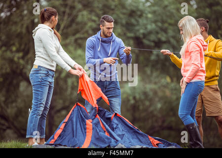 Happy amici impostazione della loro tenda Foto Stock