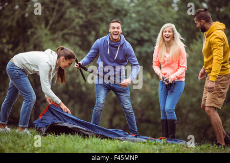 Happy amici impostazione della loro tenda Foto Stock