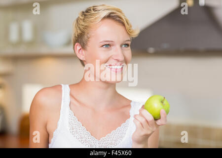 Bella bionda di mangiare una mela verde Foto Stock