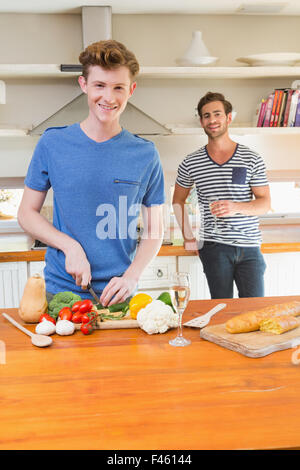 Uomo felice come tagliare le verdure in cucina con il mio ragazzo dietro Foto Stock