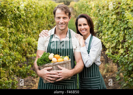 Sorridente imprenditore giovane tenendo un cesto di verdure Foto Stock