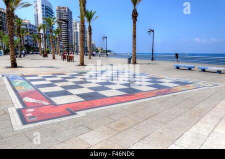 Una vista della Corniche a Beirut, in Libano e la scacchiera gigante verniciate sul pavimento. Una strada asfaltata fiancheggiata da palme Foto Stock