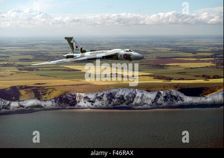 Un solitario Avro Vulcan bomber accelera il mare oltre il distintivo bianche scogliere della costa inglese nel Kent. Foto Stock