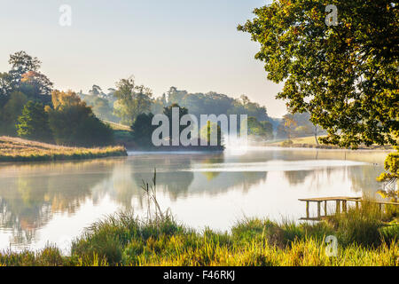 Nebbia autunnale oltre il lago a Bowood Station Wagon nel Wiltshire. Foto Stock