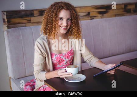 Ritratto sorridenti donna utilizzando tablet e di bere il caffè Foto Stock